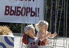 дети на качелях рядом с плакатом все на выборы