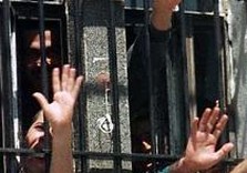 заключенные тянут руки через решетку